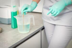 el cosmetólogo usos un palo a mezcla desinfectante dentro el agua. esterilización de herramientas. foto