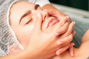 un joven caucásico mujer consiguiendo facial masaje en un spa. foto
