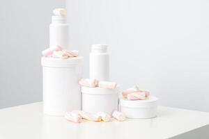 Cosmetic skincare packaging. Beauty product on white background. White jars with marshmallows on the white table. photo