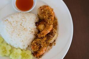 Fried shrimp with garlic and pepper and cooked Thai jasmine rice in white plate. photo