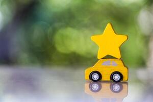 Wood yellow toy car carry a yllow star on roof against nature background. photo