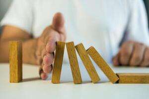 Man hand stop a domino continuous toppled photo