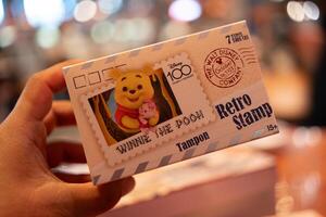 Bangkok, Thailand - April 26, 2024 Man hand holding a box of Disney 100th Anniversary Retro Stamp, MINISO photo