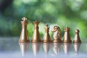 Gold chess pieces in a row on a natural background. photo