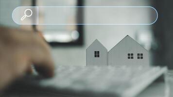 Man using keyboard with blank search bar and model home, search for find information data about home. photo