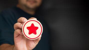 un hombre participación un rojo estrella icono en madera bloquear foto