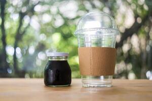 Cold coffee bottle and empty glass on the wooden table. photo