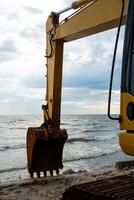 grande amarillo excavador trabajos en playa. construcción en el costa. foto
