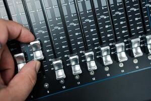 Human hand adjusting buttons on audio mixer. photo