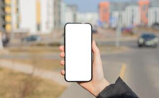 Hand holding mobile phone screen, blank smartphone, cellphone mockup, blurred city photo