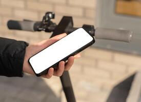 Hand using mobile phone screen mockup for renting e-scooter photo
