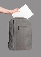 Hand putting blank book into backpack isolated photo