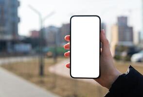 Hand holding mobile phone screen mockup, empty blank smartphone display, blurred city photo