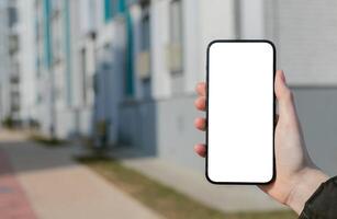 Hand holding mobile phone screen mockup, empty blank smartphone display, blurred building photo