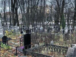 Gloomy cemetery, graveyard with tombstones, crosses and trees photo