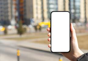 Hand holding mobile phone screen mockup, white blank smartphone display, blurred city background photo