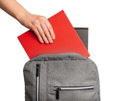 Hand putting books, textbooks into backpack, schoolbag isolated on white background photo