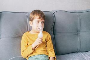 little boy sits with an inhalation mask during cough and bronchitis. Treatment with an inhaler at home photo