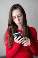 Beautiful young woman with blue eyes and long hair in a beautiful jacket watches the news on the phone photo