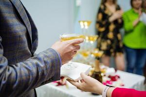 un mujer mano sirve un servilleta a un hombre debajo un vaso de champán, un chico sostiene en su mano un triangular vaso de martini, un festivo fiesta, un abierto evento a bebida alcohol. foto