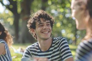 joven hombre con Rizado pelo teniendo picnic en parque con amigos. foto