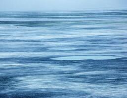 Ice surface of the river. Texture of ice shards and water. Winter background photo