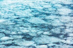 Ice surface of the river. Texture of ice shards and water. Winter background photo