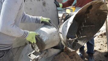 trabajador a un construcción sitio mezclas el mortero para piso maestra en un mezclador video