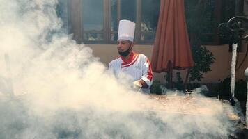 Ägypten, Hurghada - - Februar 18, 2022. Straße Lebensmittel. das Koch bereitet vor Fleisch auf das Straße. schwer Rauch um Kochen. das Koch Braten Hähnchen Fleisch auf das Grill. video