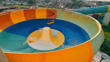 hurgada. Egipto 10.11.2021 agua parque y agua diapositivas turistas teniendo divertido en un agua deslizar. ver desde encima en dos personas montando en un inflable rueda. video