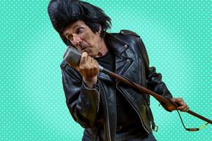 Funny portrait of mature rocker. An old singer dressed in rockabilly style in action photo