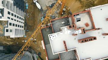 Aerial Top view on house construction. The construction crane delivers a cement solution. Construction workers fill the terrace of the house with cement. video