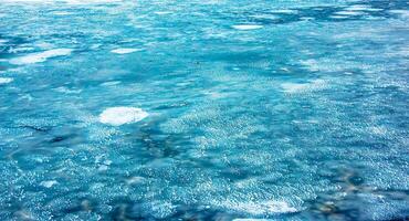 Ice surface of the river. Texture of ice shards and water. Winter background photo