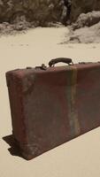 en bit av bagage Sammanträde på topp av en sandig strand video