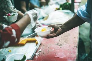 Volunteers are giving free food to help the hungry poor concept of food sharing photo