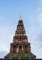 Ancient brick pagoda in Lamphun province against blue sky photo
