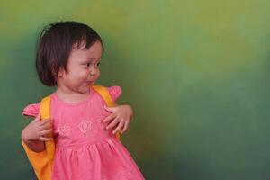 un indonesio pequeño niña vistiendo vestir y participación un bolso foto