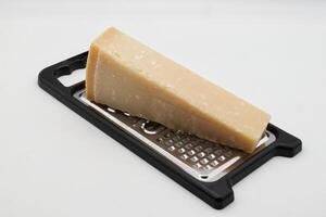 metal rallador con parmigiano reggiano queso aislado en blanco foto