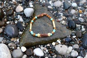 Bangle made from natural wooden materials and minerals on the wet stones near to sea. Handcraft precious item. Jewelry accessories. photo