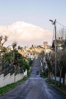 escénico ver de un residencial calle en un encantador montañoso pueblo con un mezquita en el distancia foto