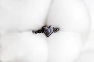 Elegant tiny handmade silver ring with heart on a background of cotton flowers. Jewelry accessories. photo