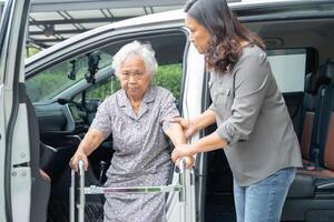 asiático mayor mujer paciente sentado en caminante preparar obtener a su auto, sano fuerte médico concepto. foto