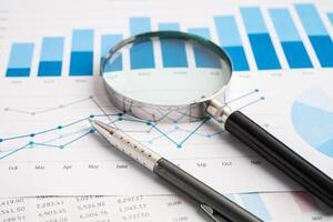 Magnifying glass on spreadsheet and graph paper. Financial development, Banking Account, Statistic, Investment Analytic research data economy, Business. photo