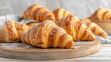 Assortments of fresh french croissants on a light wooden table in a bakery. photo