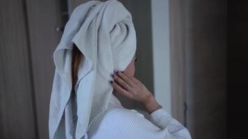 Asian woman wearing a bathrobe and towel on her head walks into the bathroom. Morning routine activities. video