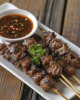 Satay Served with Soy Sauce, Artfully Arranged on a White Plate with a Small Bowl of Sauce Nearby. Perfect for a Restaurant Menu. photo