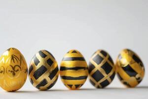 Easter golden and black decorated eggs stand in a row on white background photo