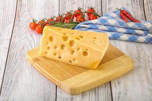Maasdam cheese piece over board photo