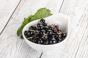 Juicy black currant berries in the bowl photo