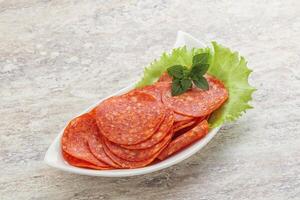 Sliced pepperoni sausage in the bowl photo